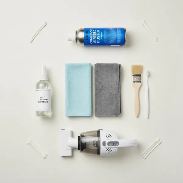 A collection of essential speaker cleaning tools, including microfiber cloths, soft brushes, and a vacuum attachment, neatly arranged.